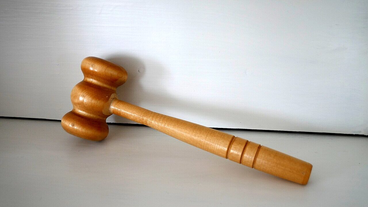 A wooden judge gavel resting on a sounding block